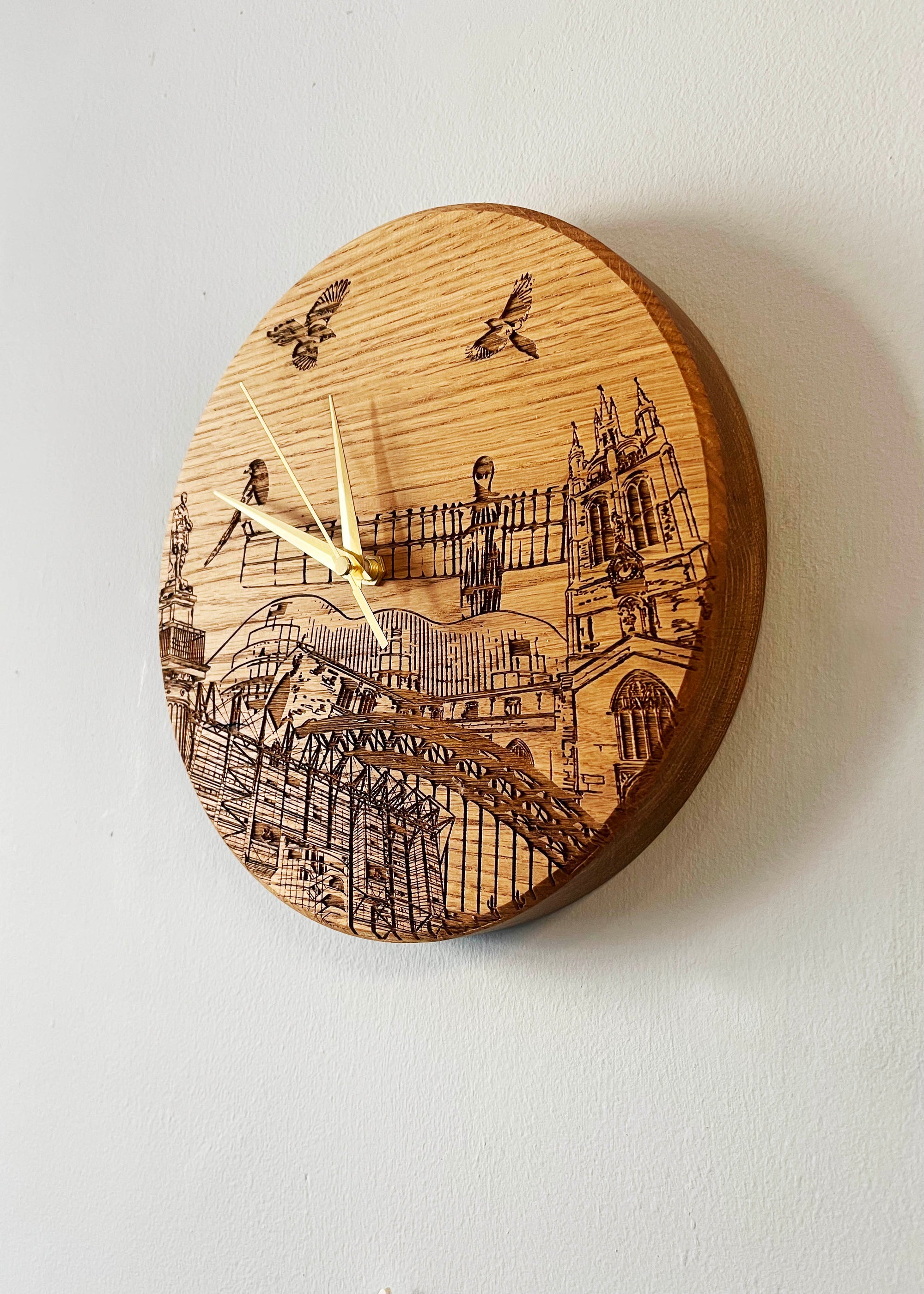 Laser engraved solid oak clock on mantle piece with stag ornaments. Engraving on the clock features landmarks such as St James' Park, Greys Monument, The Glasshouse, Newcastle Cathedral, The Tyne Bridge, Angel of the North and Newcastle Cathedral. 